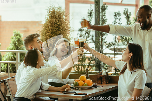 Image of Young group of friends drinking beer and celebrating together