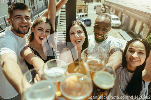Image of Young group of friends drinking beer and celebrating together