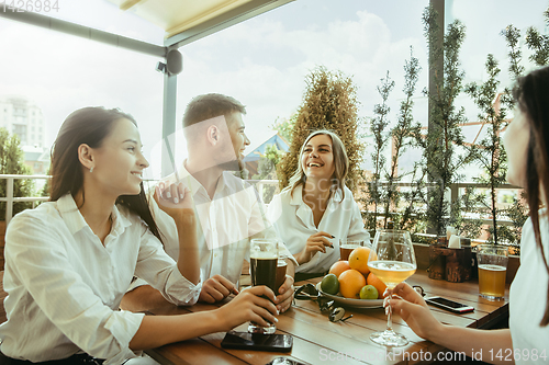 Image of Young group of friends drinking beer and celebrating together