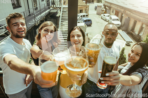 Image of Young group of friends drinking beer and celebrating together