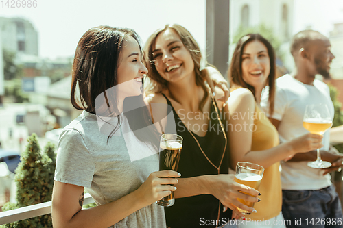 Image of Young group of friends drinking beer and celebrating together