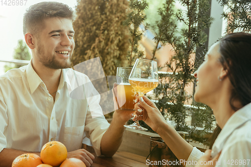 Image of Young friends or couple drinking beer and celebrating together