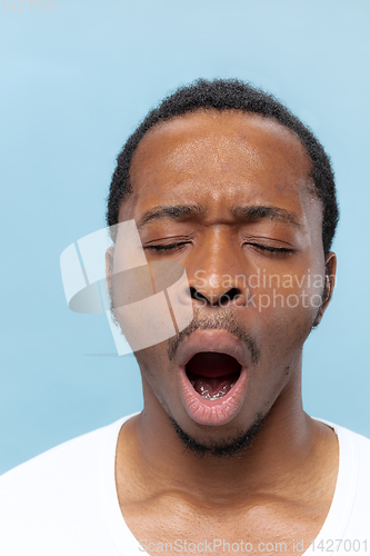 Image of Close up portrait of young man on blue background.