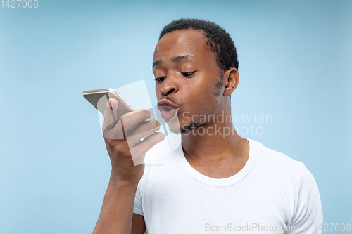 Image of Half-length close up portrait of young man on blue background.