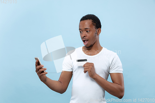 Image of Half-length close up portrait of young man on blue background.