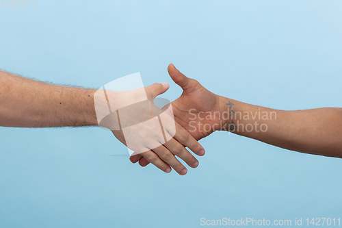 Image of Close up shot of human holding hands isolated on blue studio background.