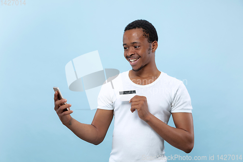 Image of Half-length close up portrait of young man on blue background.