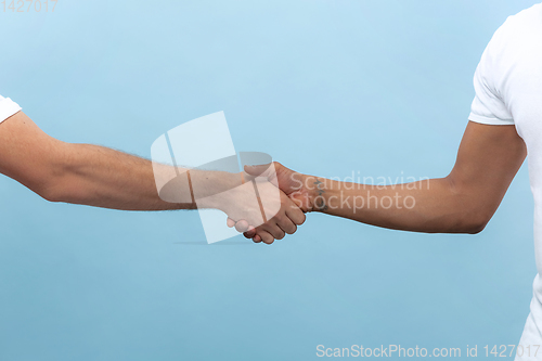 Image of Close up shot of human holding hands isolated on blue studio background.