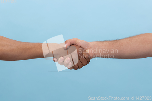 Image of Close up shot of human holding hands isolated on blue studio background.