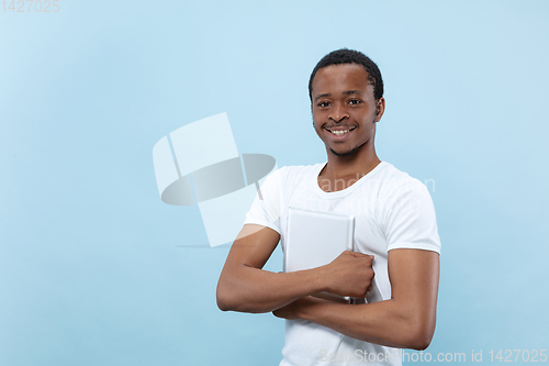 Image of Half-length close up portrait of young man on blue background.