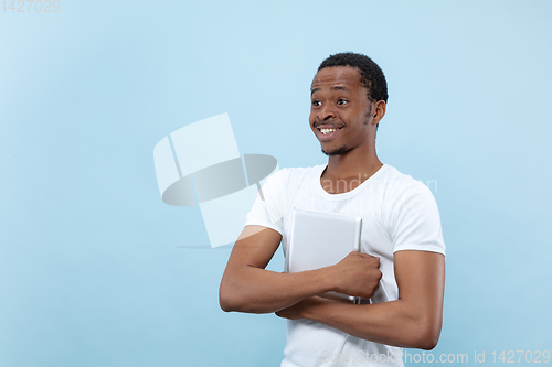 Image of Half-length close up portrait of young man on blue background.