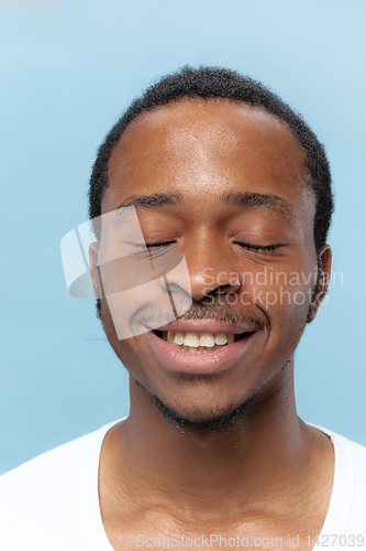 Image of Close up portrait of young man on blue background.