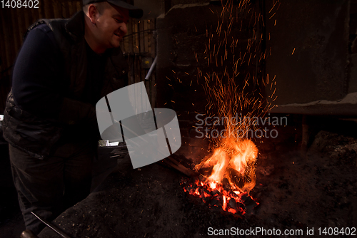 Image of young traditional Blacksmith working with open fire