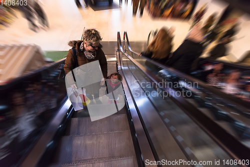 Image of young mother and her little daughter on escalator in shopping ma
