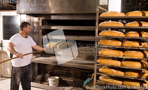 Image of bakery worker taking out freshly baked breads