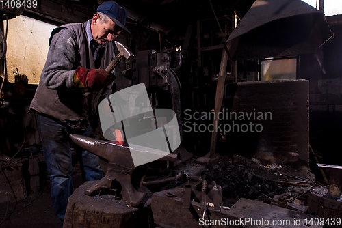 Image of blacksmith manually forging the molten metal