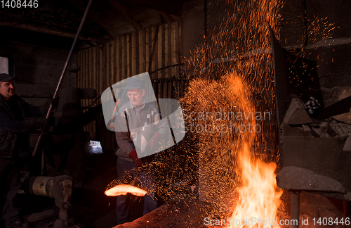 Image of blacksmith workers using mechanical hammer at workshop