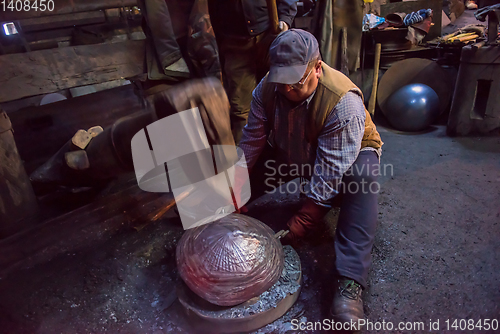 Image of blacksmith workers using mechanical hammer at workshop