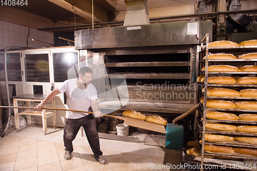 Image of bakery worker taking out freshly baked breads