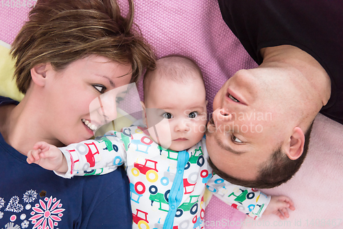 Image of Top view of smiling young couple lying with their baby