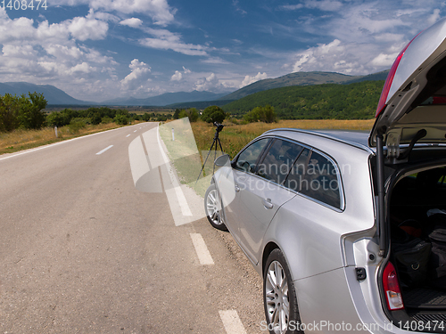 Image of profesional DSLR camera on a tripod at asphalt road in beautiful