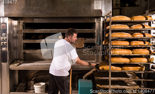 Image of bakery worker taking out freshly baked breads