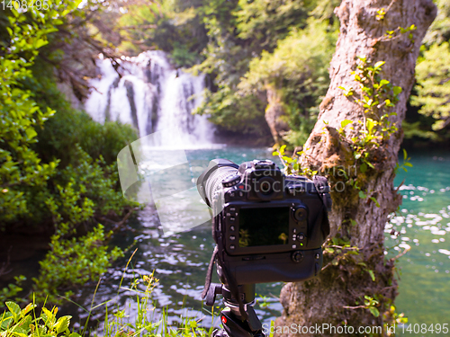 Image of profesional DSLR camera on a tripod at beautiful waterfall