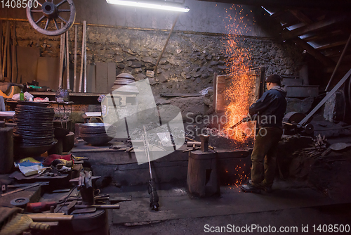 Image of young traditional Blacksmith working with open fire