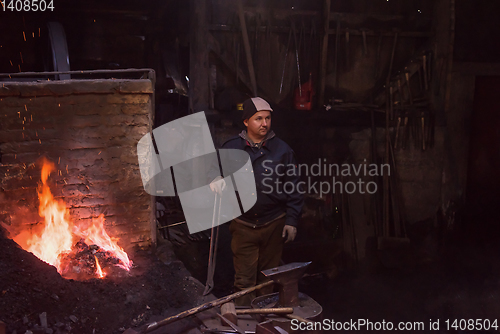 Image of young traditional Blacksmith working with open fire