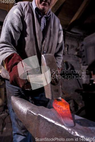 Image of blacksmith manually forging the molten metal