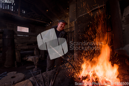 Image of young traditional Blacksmith working with open fire