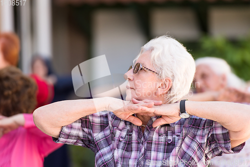 Image of senior woman exercising with friends