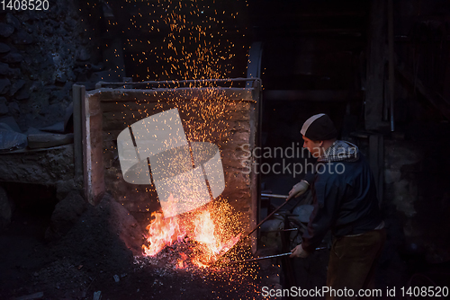 Image of young traditional Blacksmith working with open fire