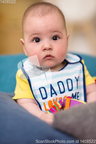 Image of baby boy sitting between the pillows on sofa