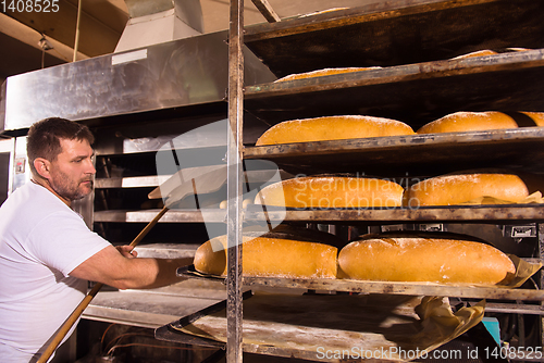 Image of bakery worker taking out freshly baked breads