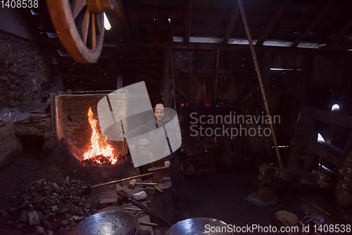 Image of young traditional Blacksmith working with open fire