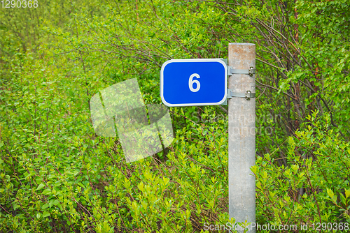 Image of Milepost mileage kilometrs on roadside  in bushes