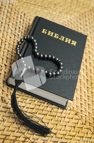 Image of Rosary on Bible put on a straw table surface