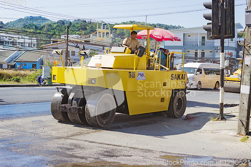 Image of  Workers operating asphalt paver machine