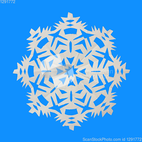 Image of Snowflake cut from paper and lies on blue background