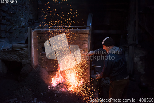 Image of young traditional Blacksmith working with open fire