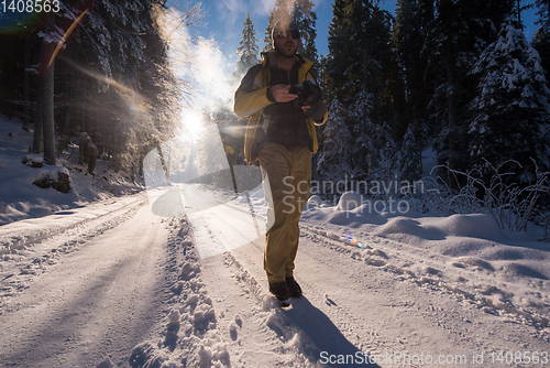 Image of young photographer walking on snowy country road