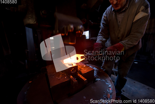 Image of blacksmith manually forging the molten metal