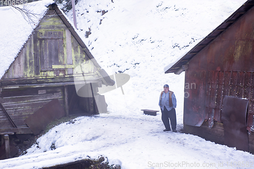 Image of traditional senior blacksmith in front of watermill