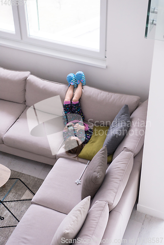 Image of little girl using a smartphone on the sofa at home