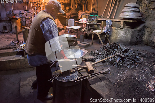 Image of traditional blacksmith manually forging the molten metal