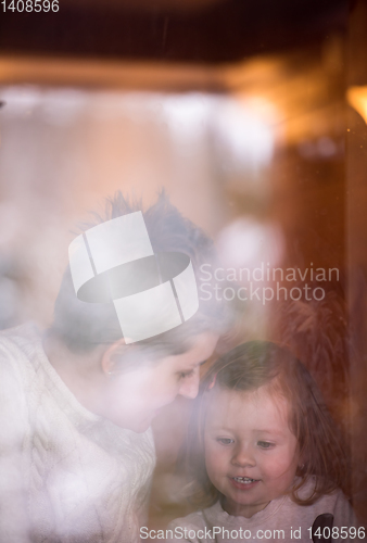 Image of young mother and little cute daughter playing near the window