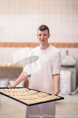 Image of A young baker holding raw product of white dough