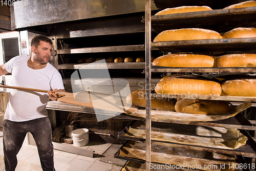 Image of bakery worker taking out freshly baked breads