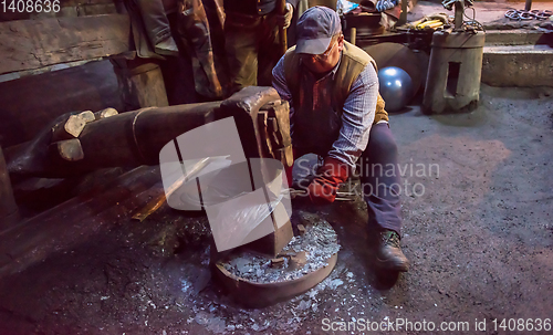 Image of blacksmith workers using mechanical hammer at workshop